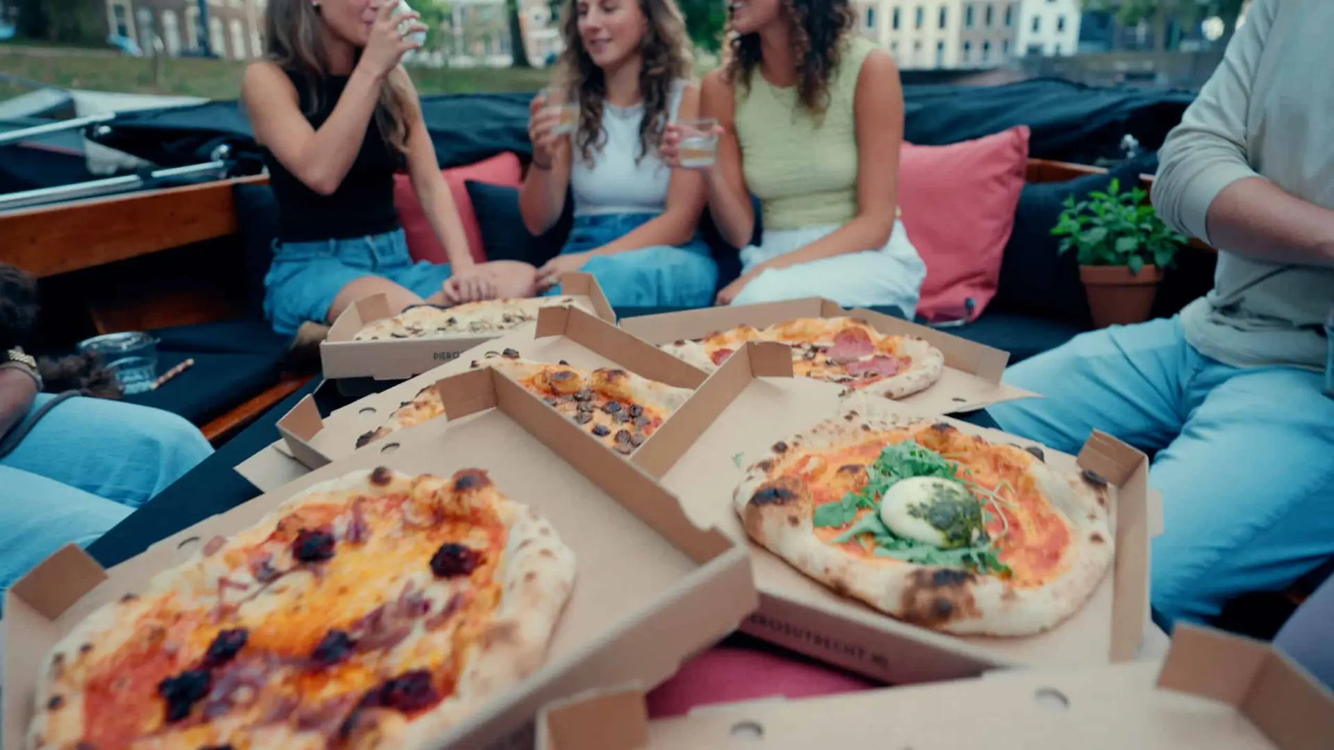 Vriendinnen eten pizza aan boord op de luxe sloep in Amsterdam